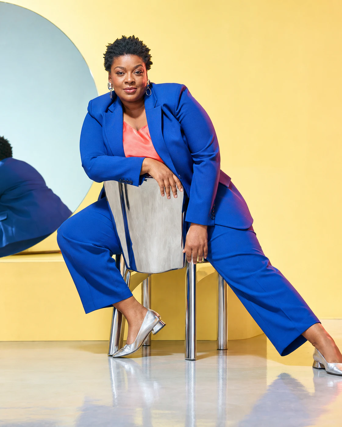 Campaign image with a chrome chair and blue suit