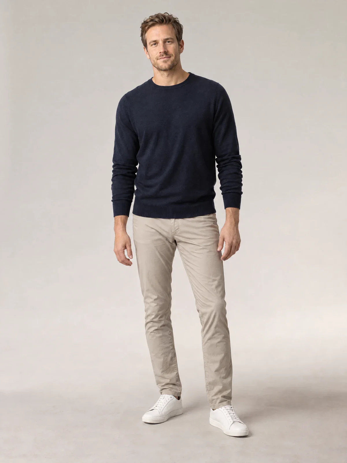 Studio photo of a man in a navy sweater and light chinos, used as a fit photo