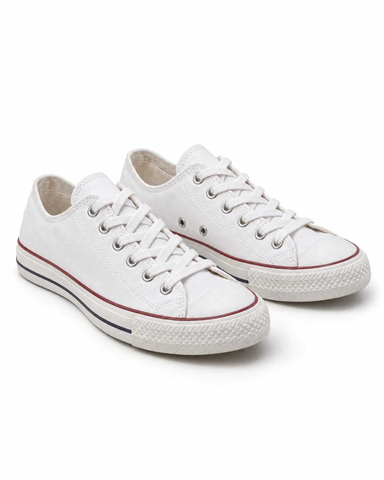 Pair of white canvas sneakers without a logo, front three-quarter view on a white background
